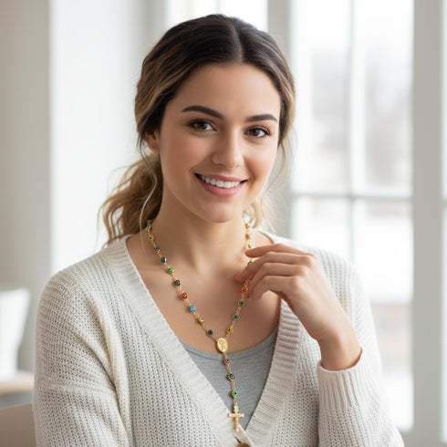 A smiling woman wearing a cream sweater and a Turkish evil eye necklace sits indoors by large bright windows.